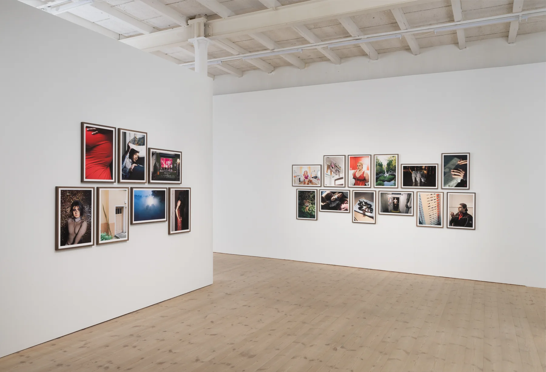 Installation view: two walls of framed photographs meeting at a corner of the gallery.