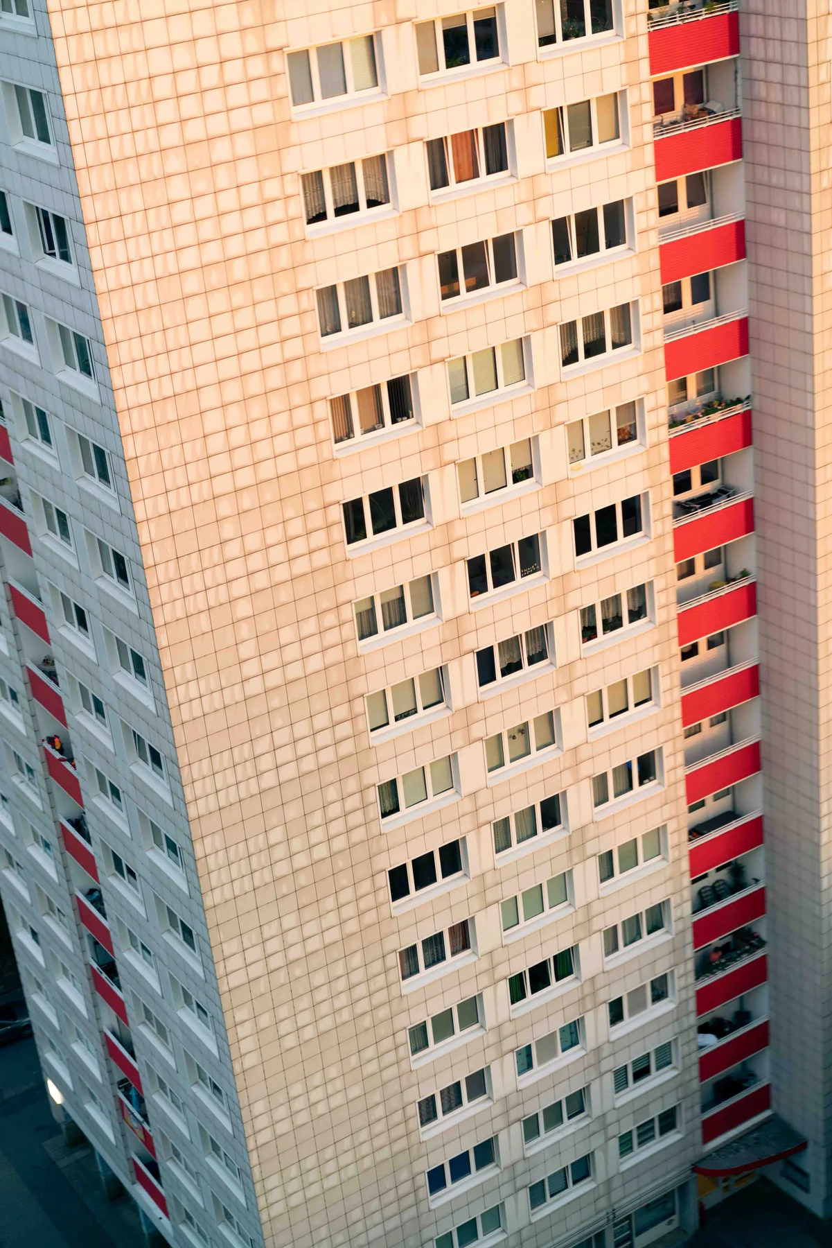 A Berlin high-rise facade at dusk, red balconies running down one side.