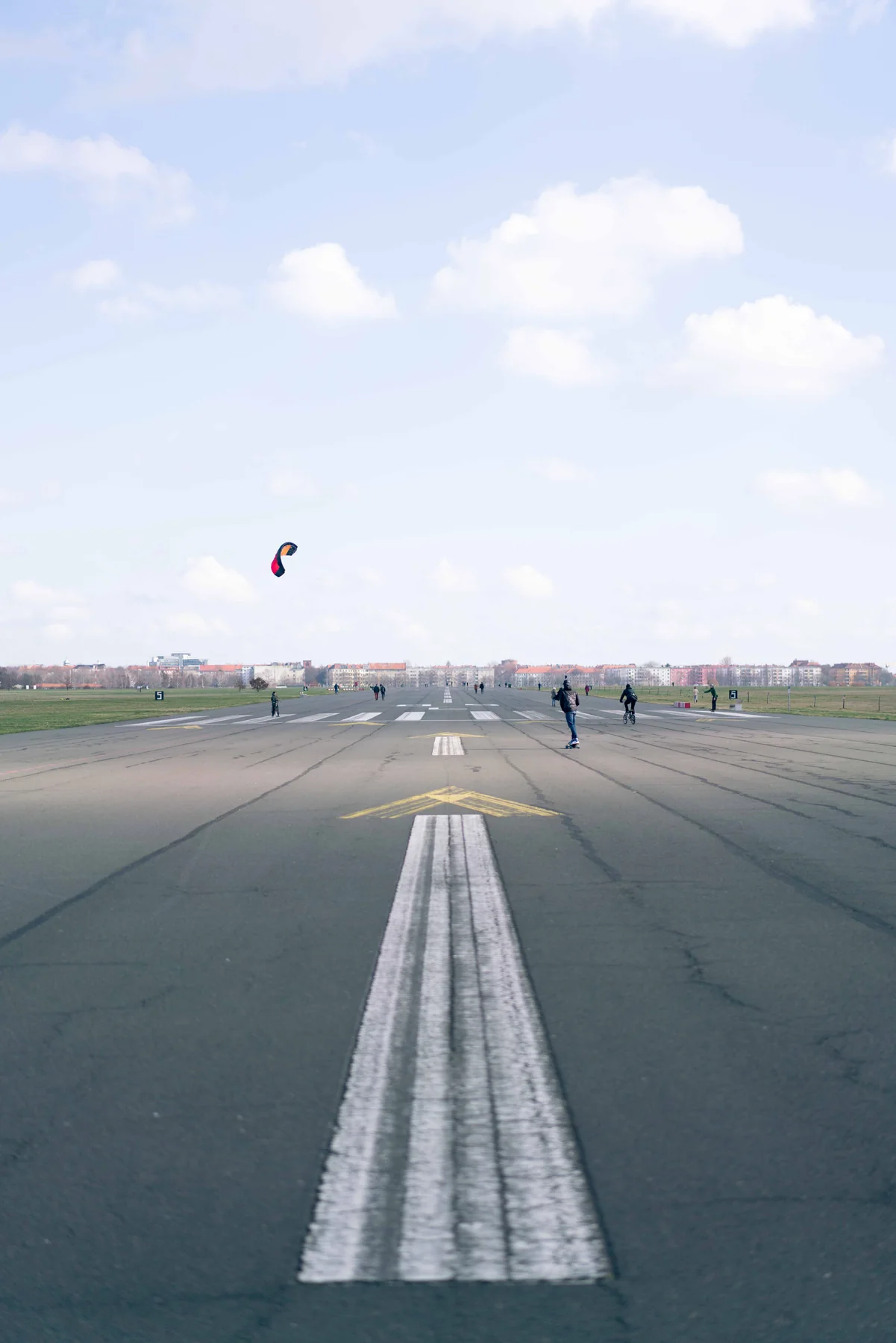 The runway markings at Tempelhof field, a kite far in the distance.